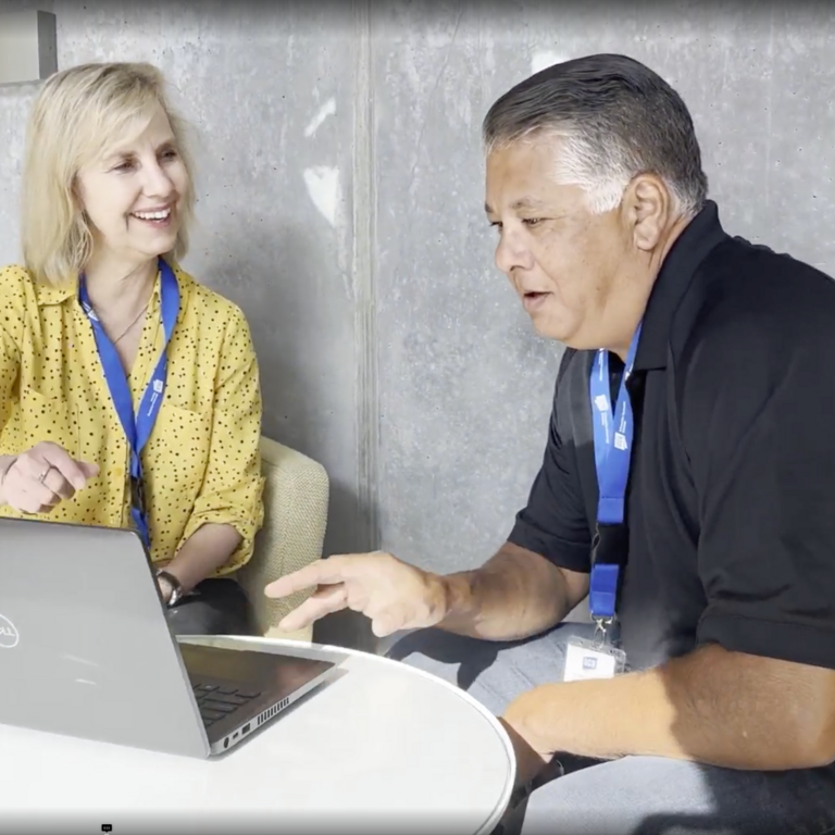 Two ITS staff sit next to each other and look at a laptop
