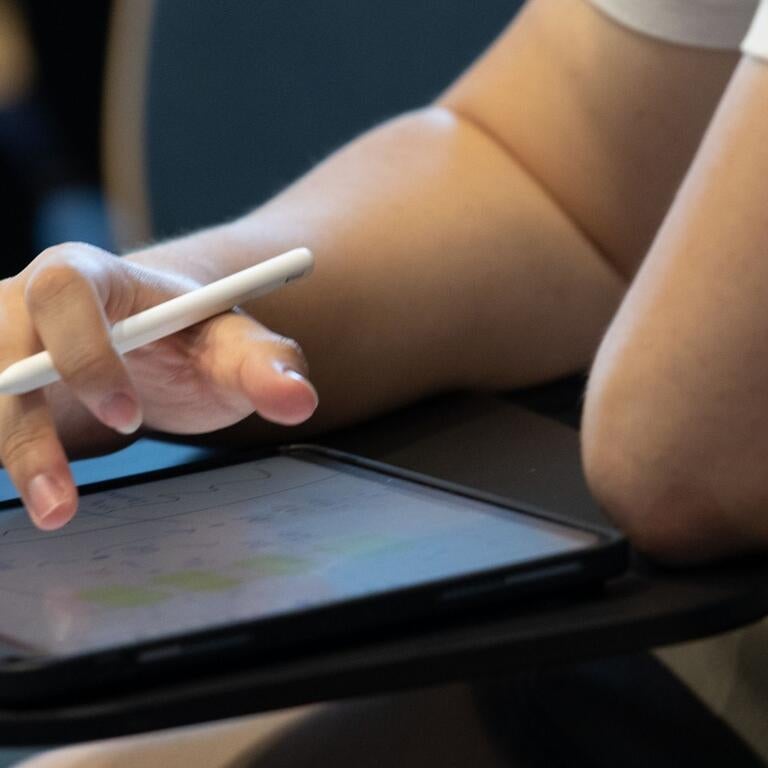 hand taps computer screen and holds a pen