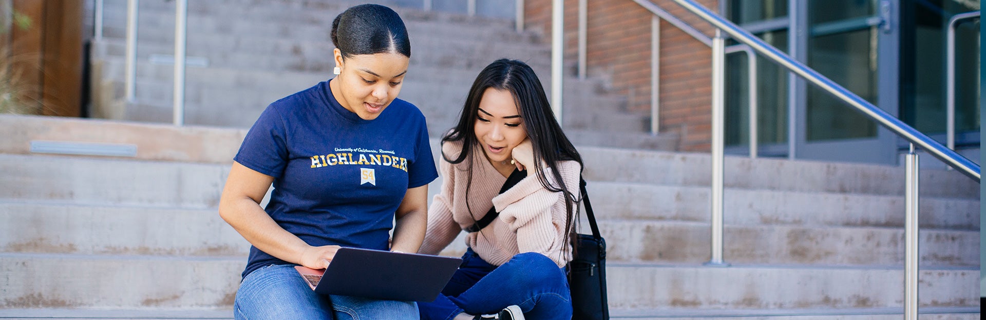 students sitting on steps with laptop