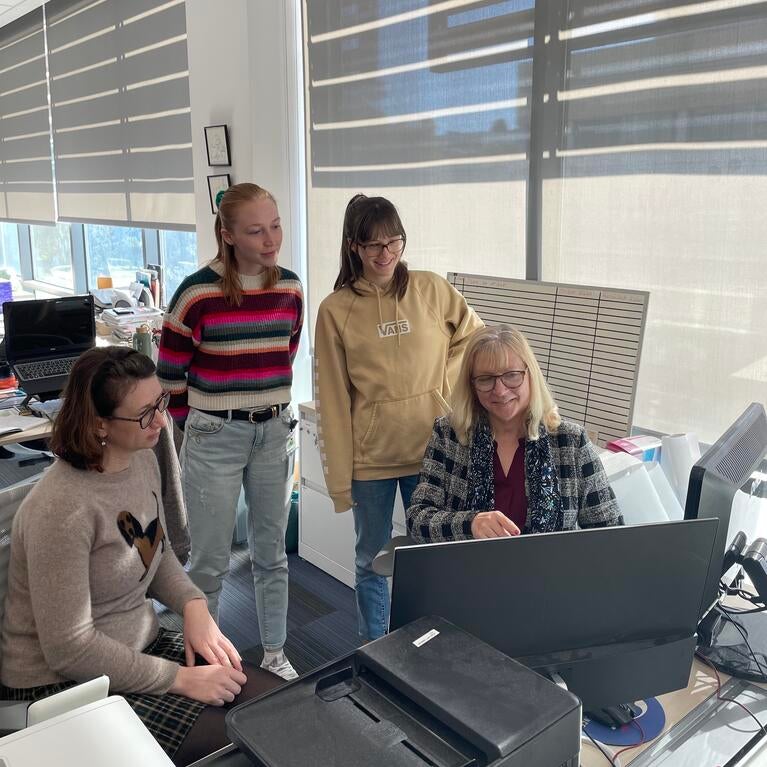 Dr. Iryna Ethell sitting at a computer surrounded by students