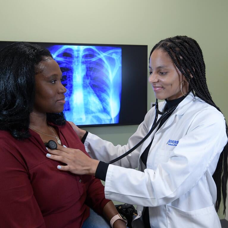 student checking the heart of a patient