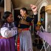 Leticia "Lety" Gallardo Martínez, band conductor of Mujeres del Viento Florido, helps UCR's Xochitl Chávez adjust a colorful belt called a tsum before a performance.