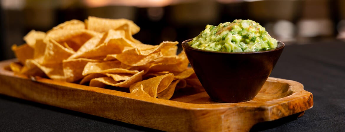 tortilla chips and guacamole served on a wooden tray