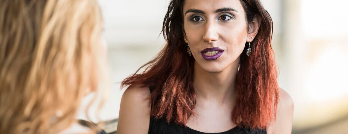 Transgender woman talking with a person whose back is to the camera.