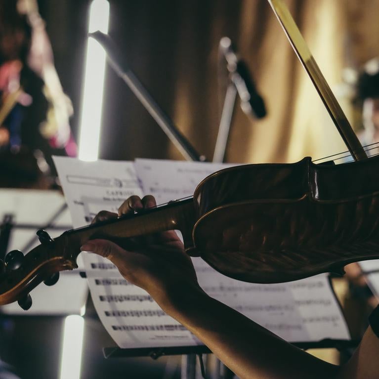 Person playing violin with sheet music on stand