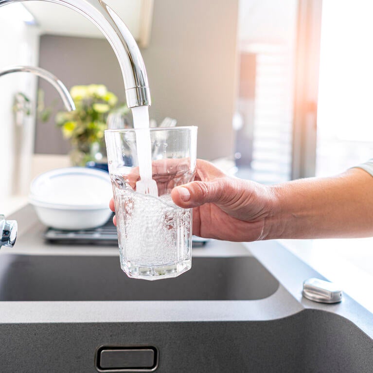 A person fills a glass with water from a faucet