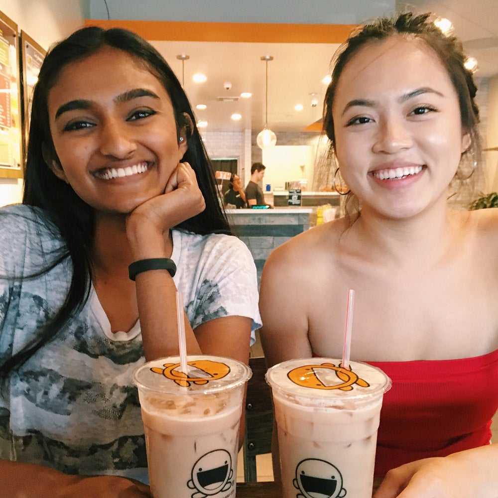 Two UCR students happily enjoying boba tea drinks.