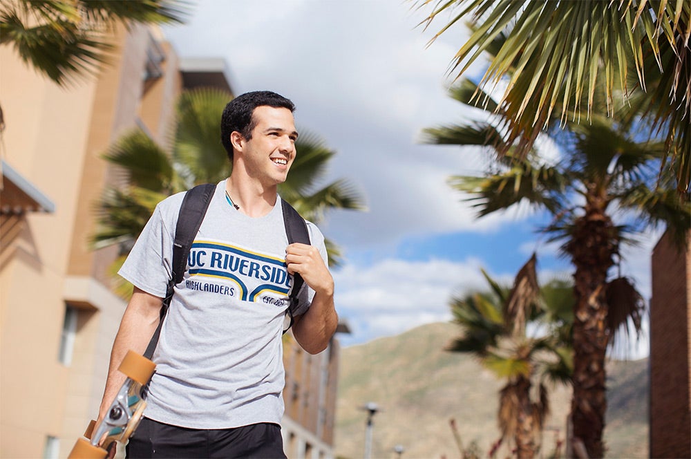 A male student walks through a sidewalk path of the UCR residence halls.