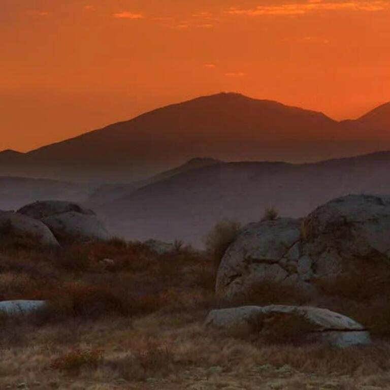 A vibrant orange sunset over dark mountains.
