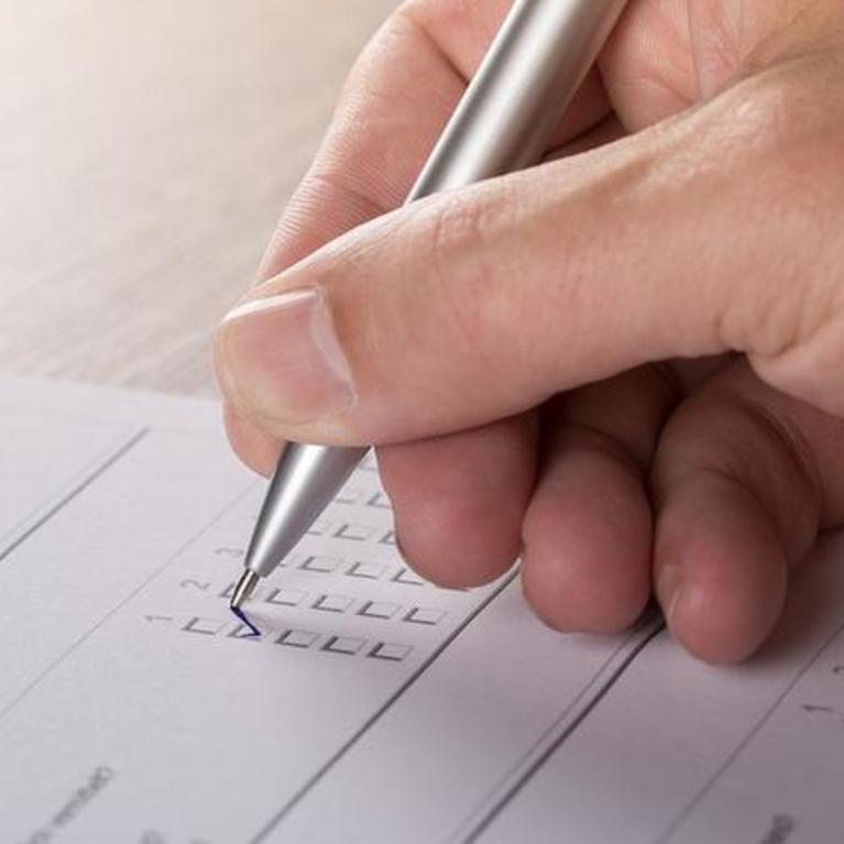 Hand with pen, filling out survey