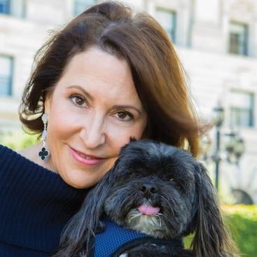 Susan Atherton grinning as she hugs her dog