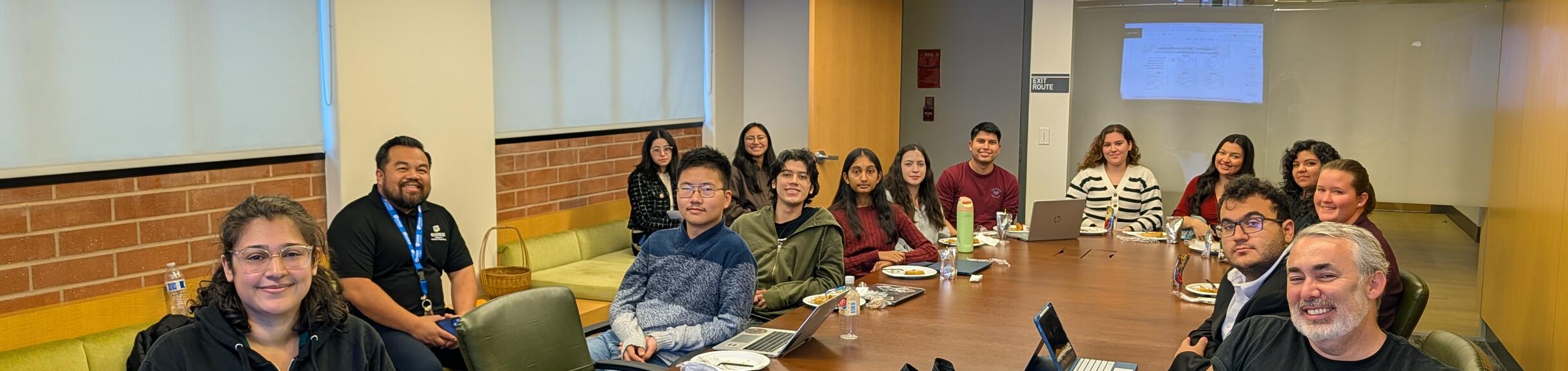 Scholars joining around a conference table sharing their research