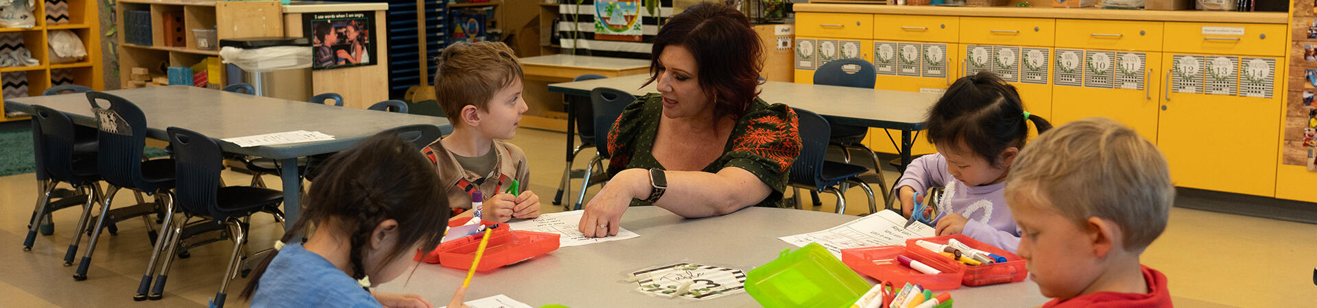 teacher helping children at table