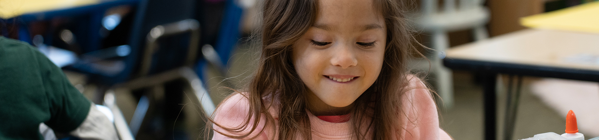 kindergartener smiling at table while writing