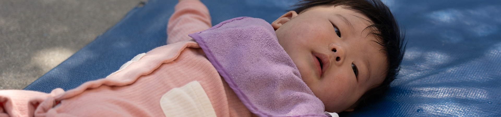 infant laying on mat on back