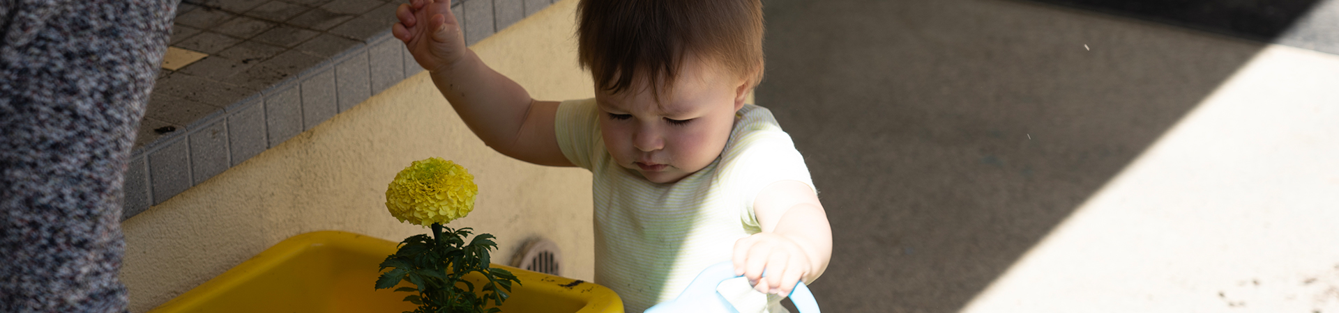 infant watering plants outside