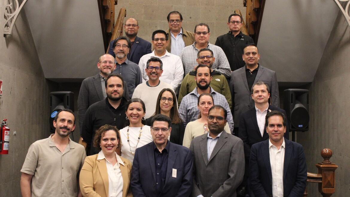 Twenty-two participants from the Binational Working Group on Zero-Emission Vehicles pose on a staircase at the Casa de la Universidad de California in Mexico City.