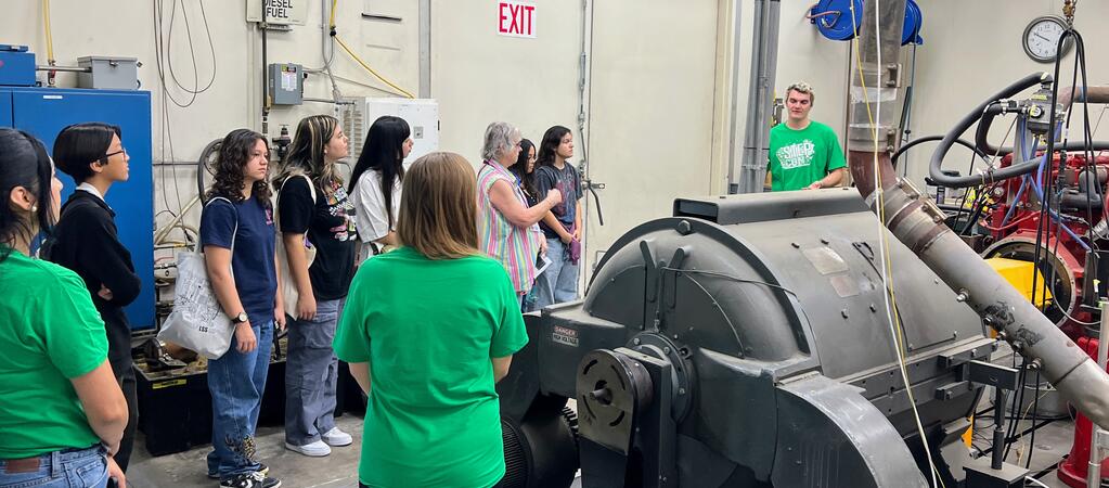 High school students listen to a CE-CERT graduate student explaining the Heavy-Duty Engine Dynamometer during a lab tour at STEPCon 2024.