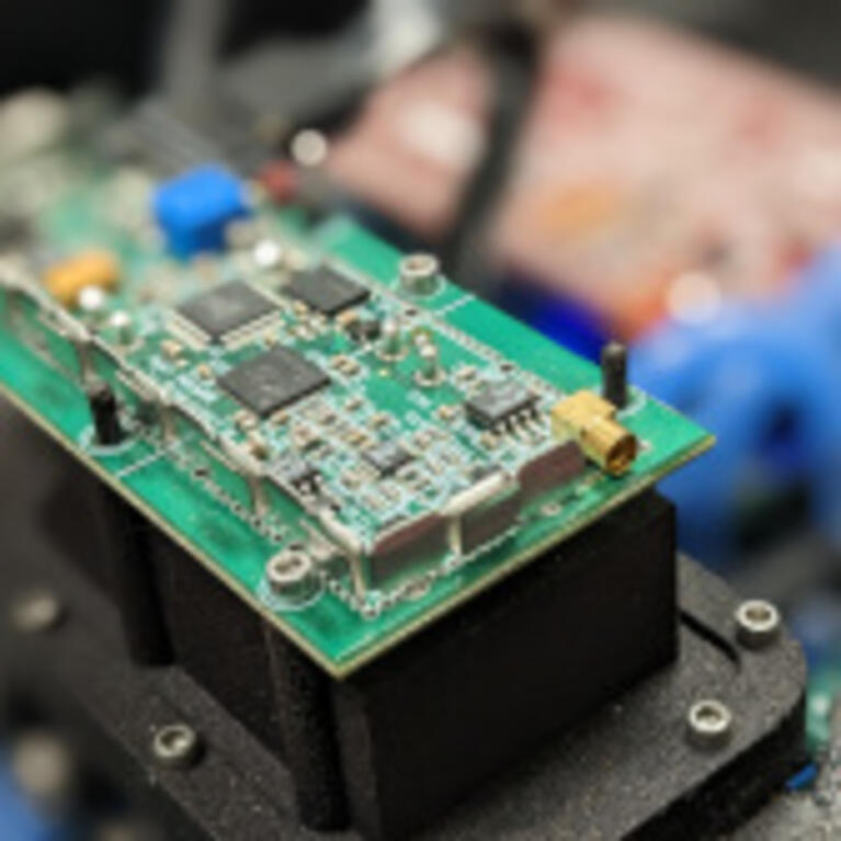 A detailed image of a circuit board with chips and other electronic components, mounted on a black structure.