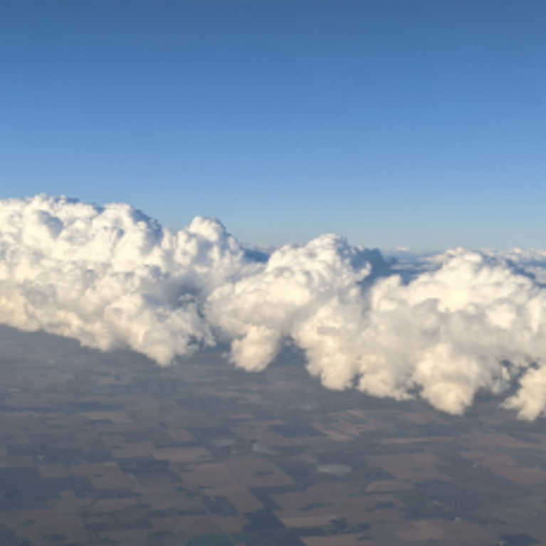 Aerial view of a landscape with a large roll of cumulus clouds stretching across the sky, photographed as part of atmospheric studies by Sarah Petters at UCR CE-CERT.