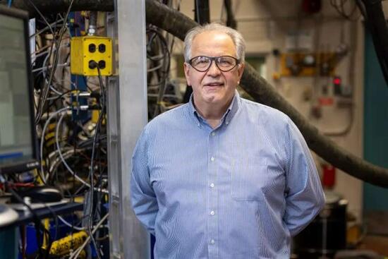 André Boehman stands in a laboratory environment with industrial testing equipment in the background, representing his role as co-director of the Hydrogen Engine Alliance of North America (H2EA-NA).