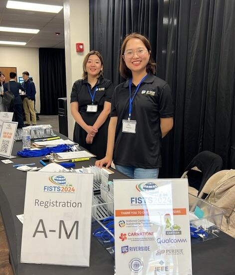 Two students standing at the registration desk for IEEE-FISTS 2024 International Conference for Sustainable Transportation