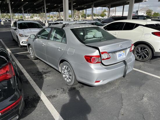 Rear view of a silver Toyota Corolla parked in a lot with a black emissions sampling hose extending from the trunk, indicating mobile emissions testing in progress.