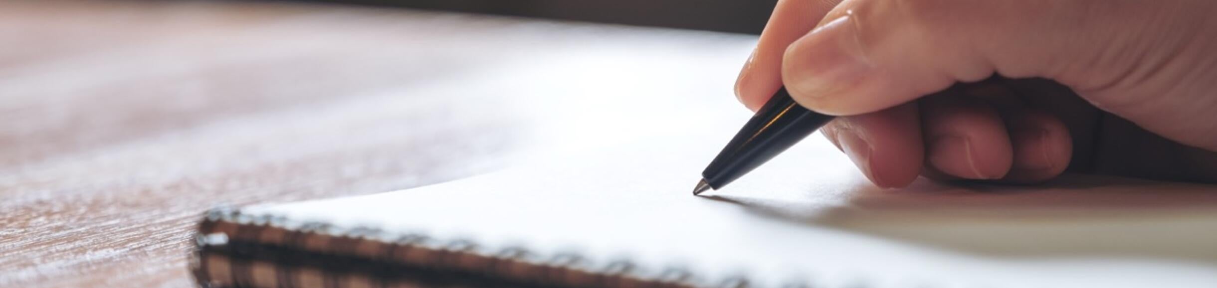 A person writing with a pen