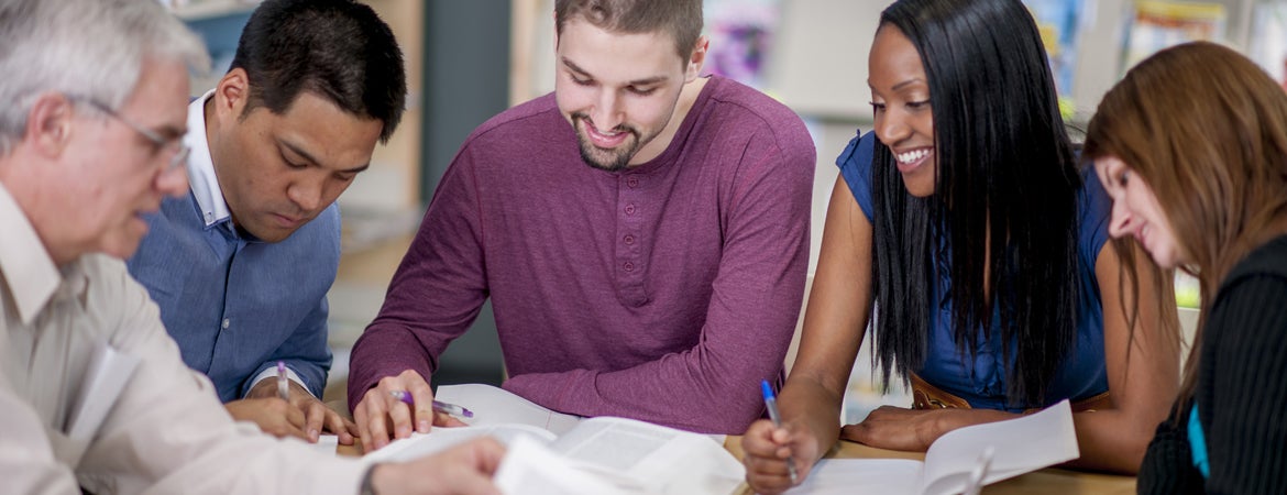 Students take notes during a small discussion session with a faculty member.