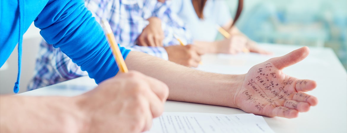 A student cheats on a test by having equations written on their hand. 