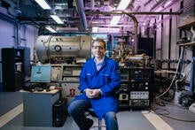 researcher sitting on a stool wearing ppe in front of equipment