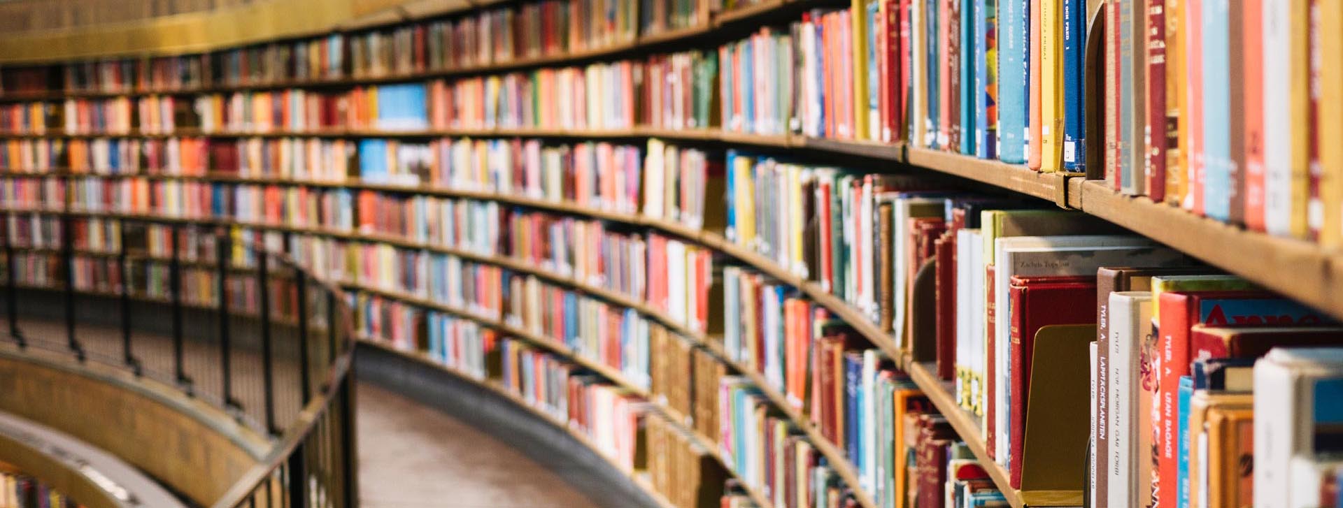 Books on long curved library bookshelves (c) Susan Yin unsplash 