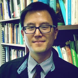 Image of Fuson Wang standing in front of a bookcase.