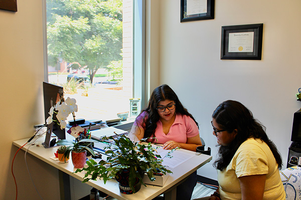 two women sitting in an office reviewing a printed document  