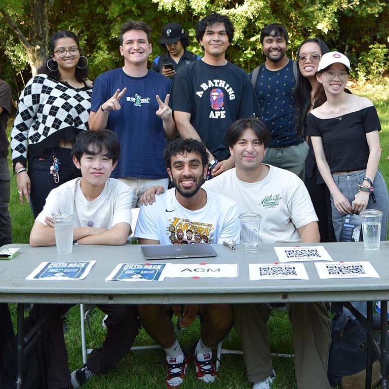 men and women members of ACM casually dressed posing outdoor in a grassy area 