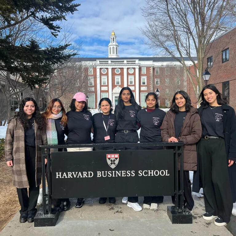 Women In Computing members standing with a banner during travel