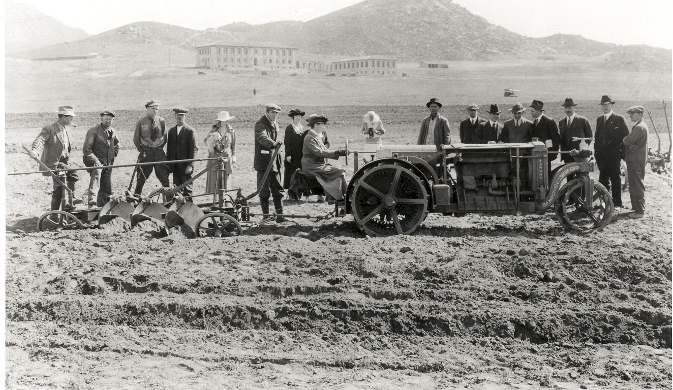 historical black and white picture of workers using machinery in a field