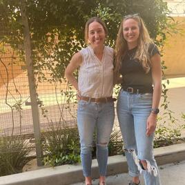 Two people standing in front of fence with climbing vines