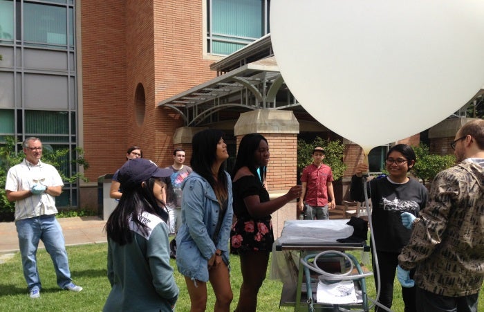 Students filling white ballon with gas.
