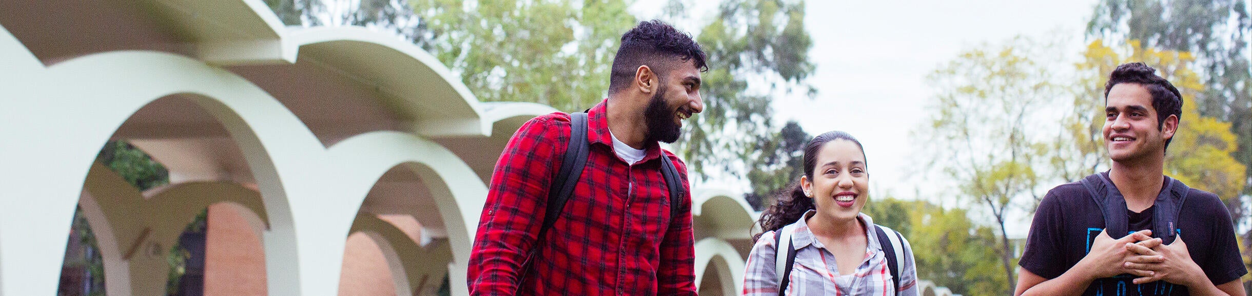 UCR students walking on campus in front of Rivera Arches