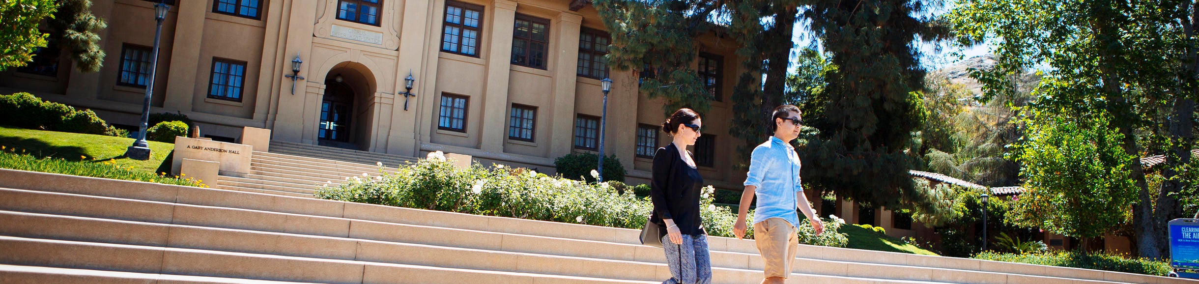 Business, two students walking in front of the School of Business