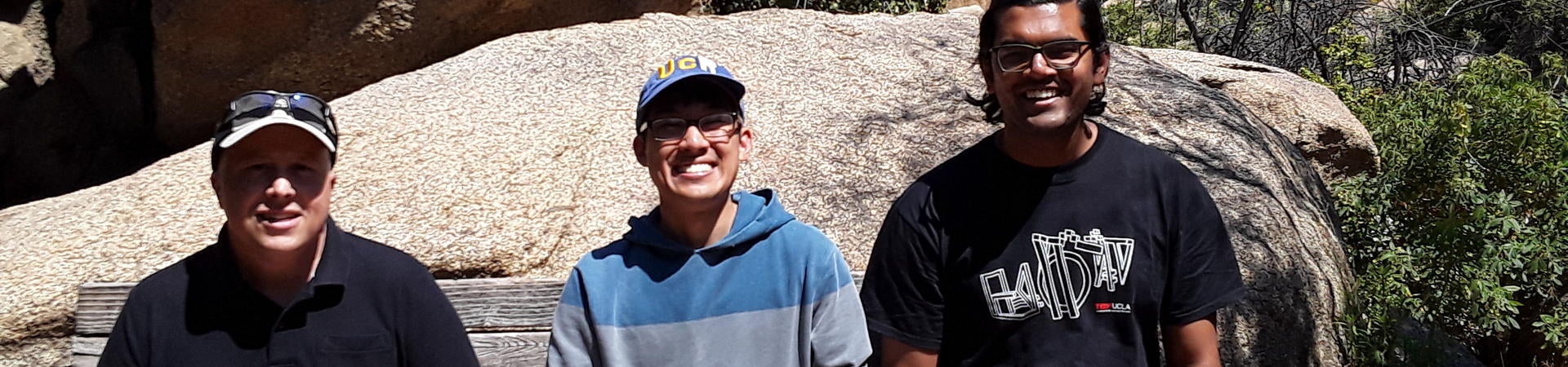 Three students sit together on a rock