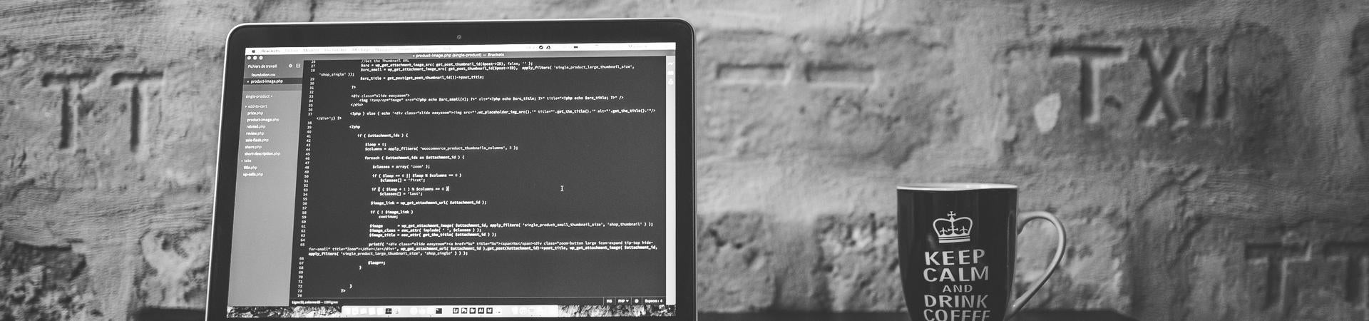 A laptop, a notebook, and a coffee mug on a desk. 