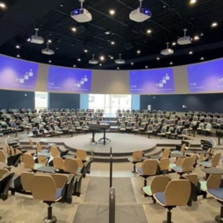 A circular seating lecture hall with a dais in the middle and projections all around the outer wall