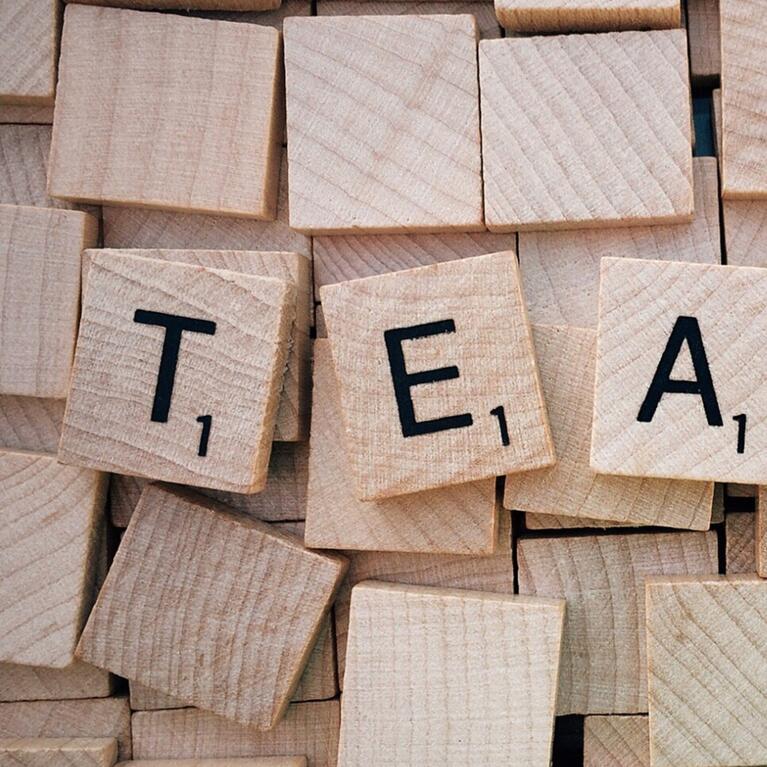 TEACH spelled out in Scrabble tiles over blank tiles