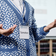 Image of a persons upper body wearing a lanyard with a badge that reads "Speaker."