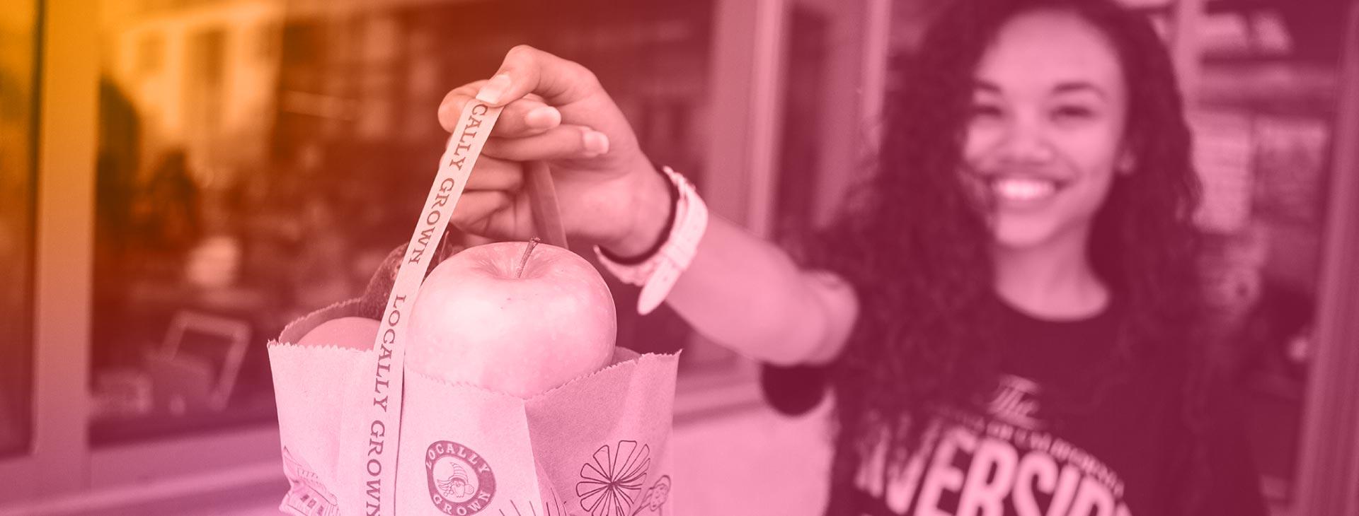 Duotone of UCR Student holding bag of free fruit.