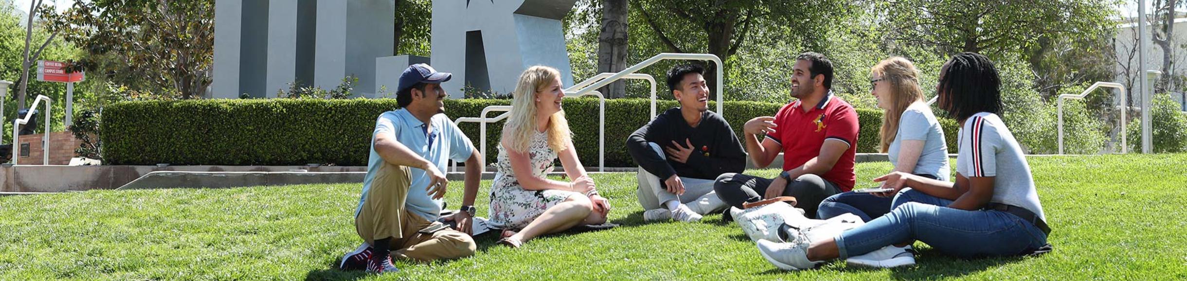 Students sitting in front of UCR Sign