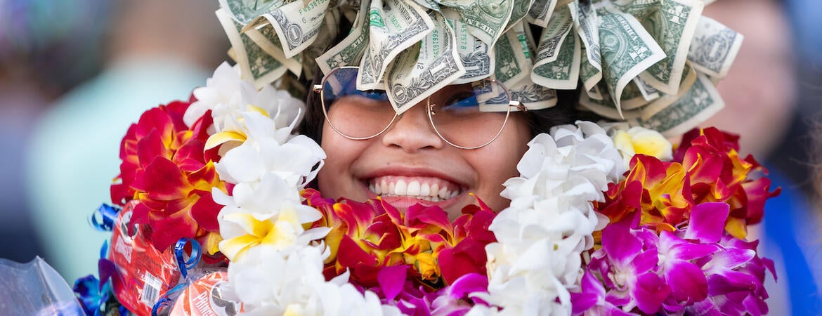 Graduate covered in floral leis and money crown