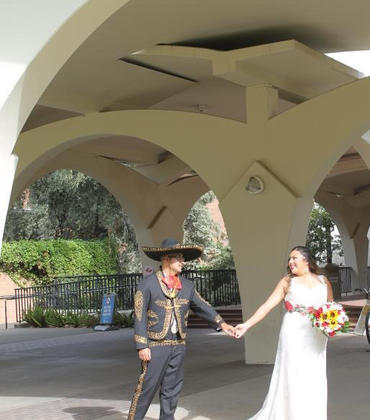 Couple poses on their wedding day under the Rivera arches at UC Riverside 